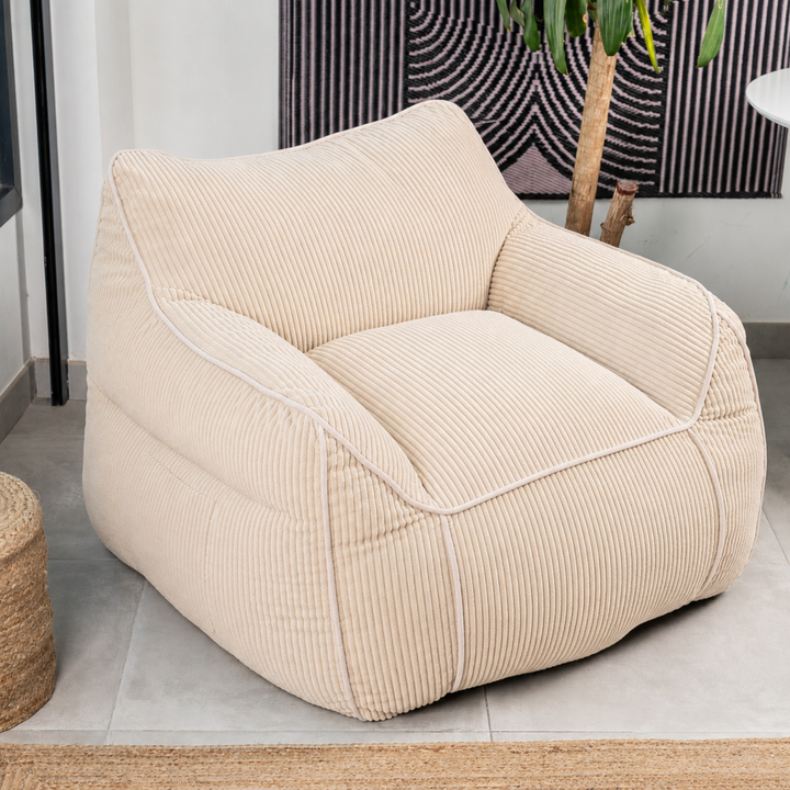 Pouf fauteuil velours côtelé beige, vue trois-quarts sur sol, forme volumineuse