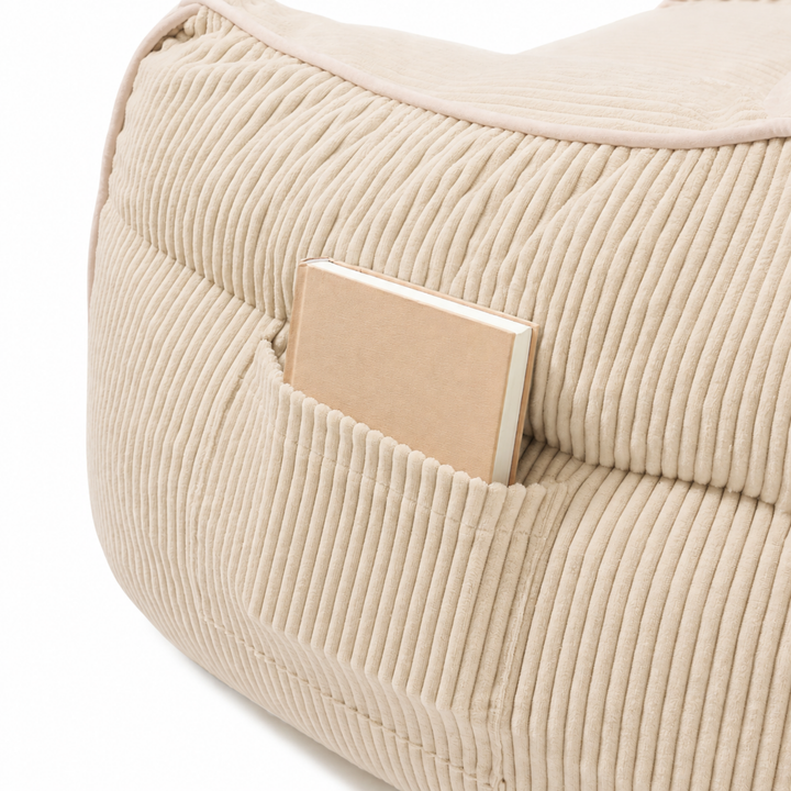 Pouf fauteuil en velours côtelé beige, détail de la poche de rangement sur le côté.