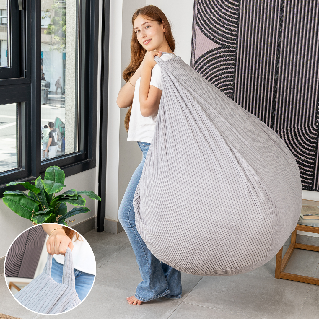 Femme soulevant le pouf poire déhoussable en velours côtelé déhoussable par sa poignée.