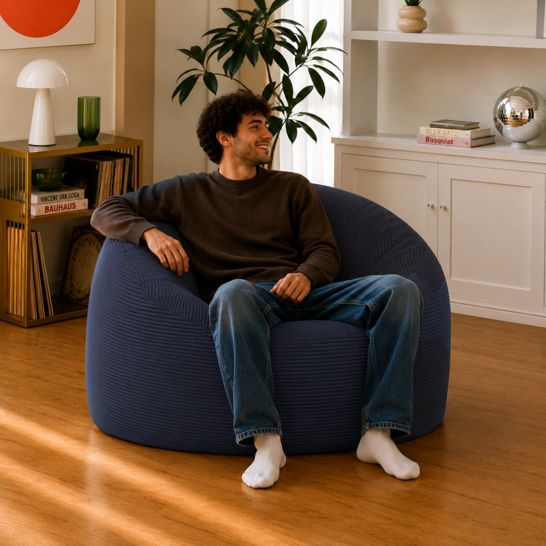 Personne assise sur un pouf déhoussable bleu foncé en velours côtelé