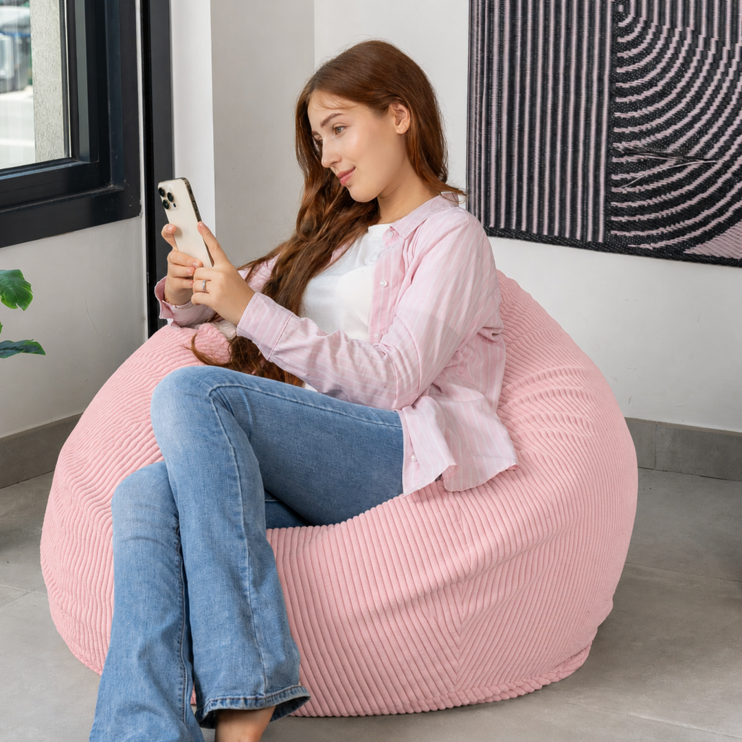 Femme assise sur un pouf poire déhoussable en velours côtelé, dans un salon