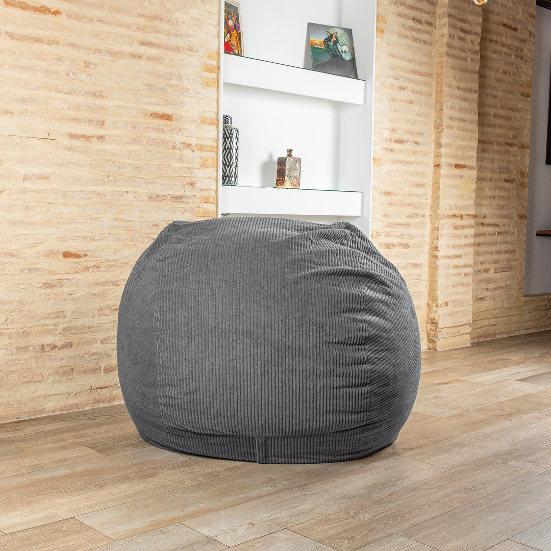 Pouf-lit convertible 2en1 gris foncé, assise ronde, dans un salon