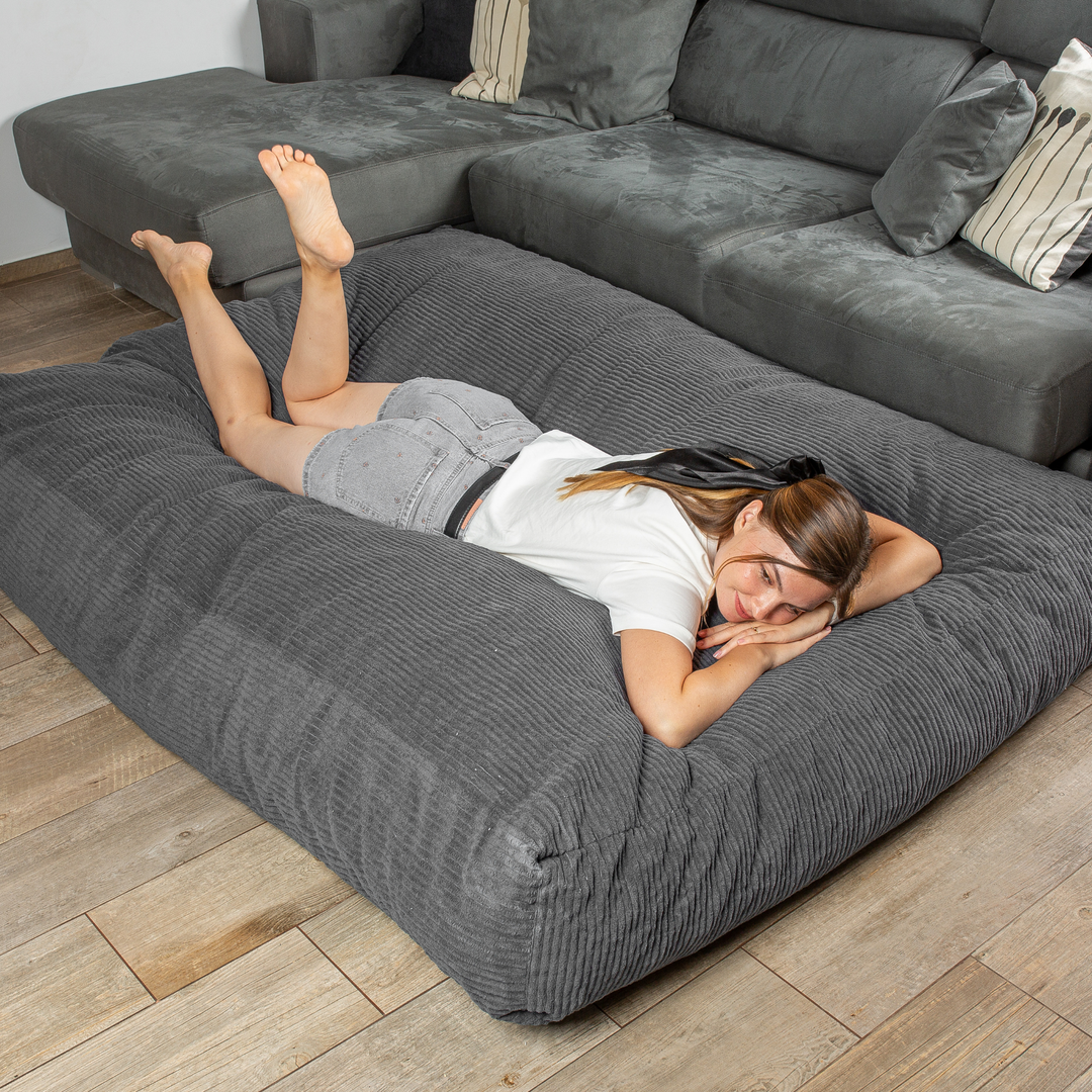 Personne allongée sur le pouf-lit convertible 2en1, utilisé en couchage pour se détendre