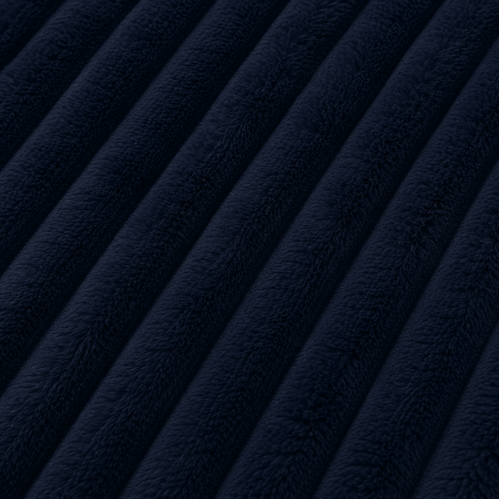 Fourrure côtelée bleu nuit : texture dense et moelleuse, lignes ondulées visibles.
