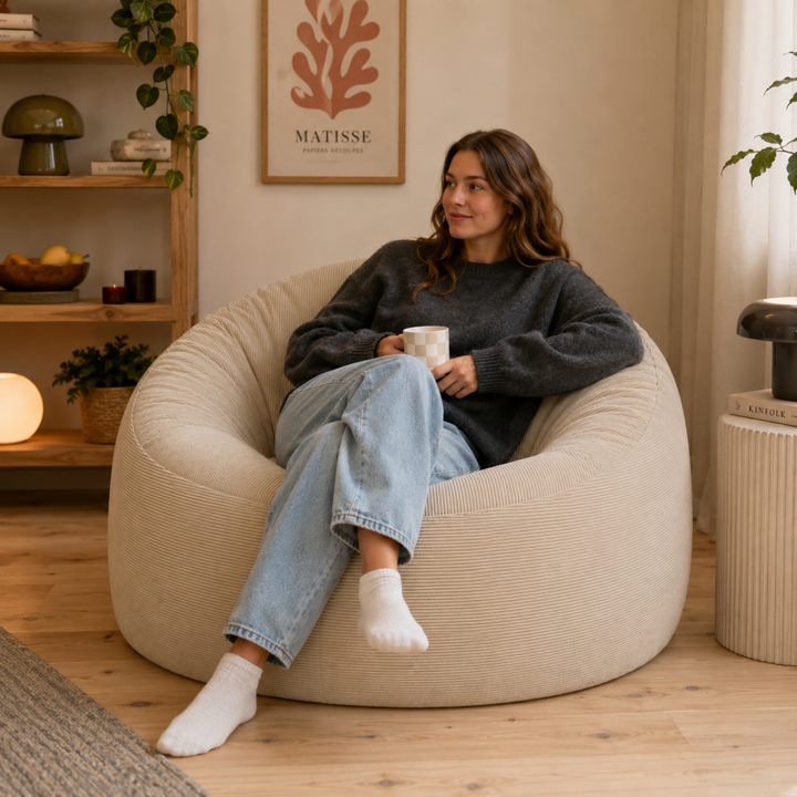 Personne assise sur un pouf déhoussable 100 cm en velours côtelé, dans un salon.