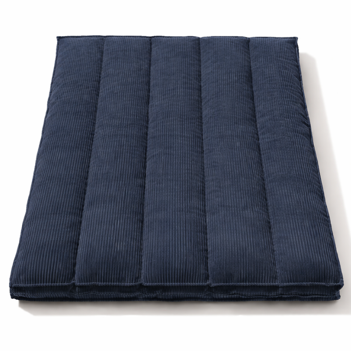 Futon déhoussable bleu foncé, coutures verticales et housse en velours côtelée.